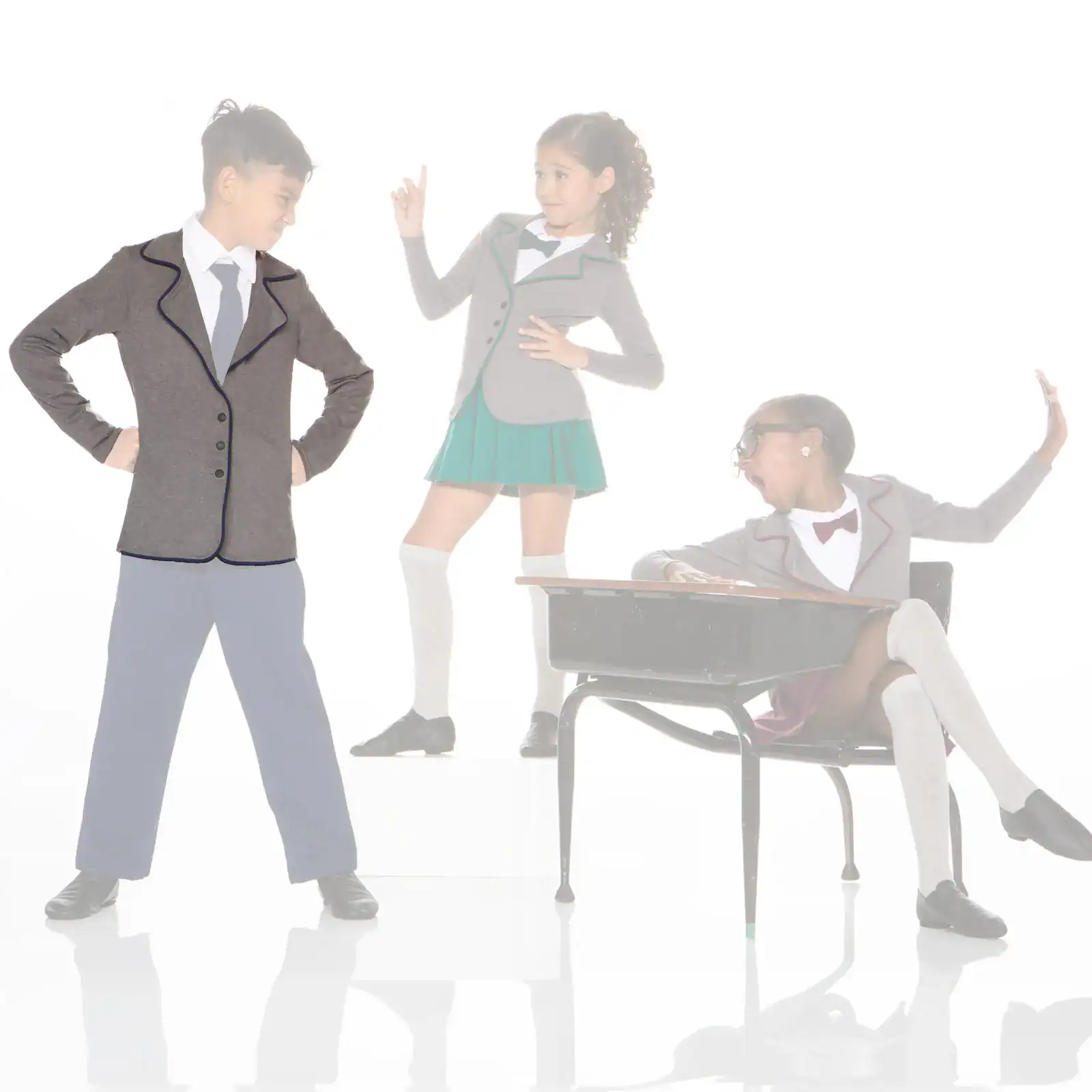 Three children in school uniforms posing around a classroom desk.