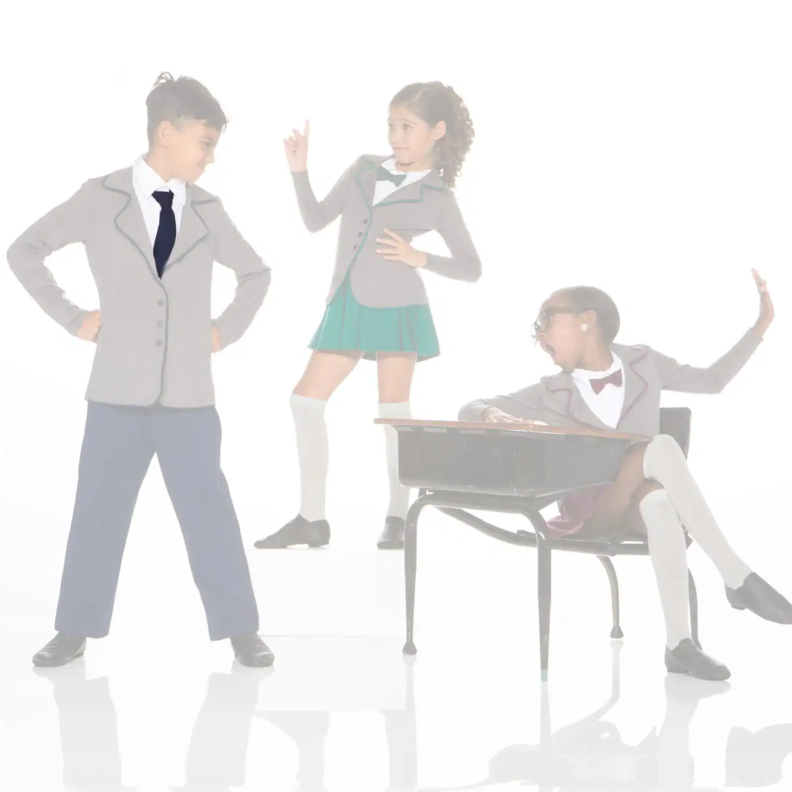 Three children in school uniforms posing around a classroom desk