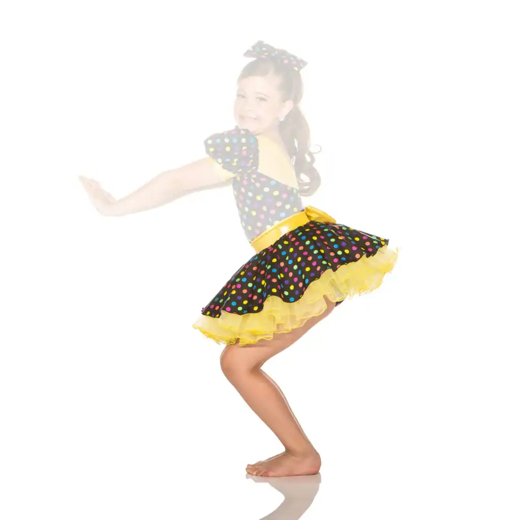 Young girl dancing in colorful polka-dot dress