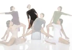 Six dancers pose in sheer costumes against white background.