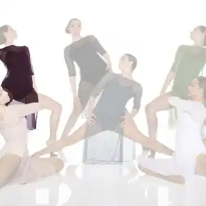 Six dancers pose in flowing dresses against white background.