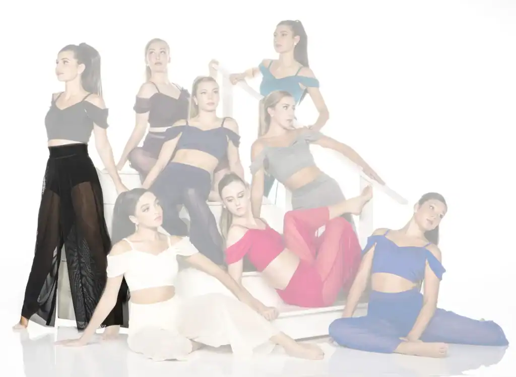 Eight dancers pose on a white staircase in colorful outfits.
