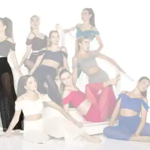 Eight dancers pose on a white staircase in colorful outfits.