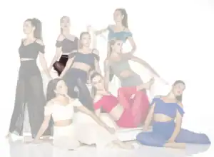 Eight women in colorful dance outfits posing on white stairs