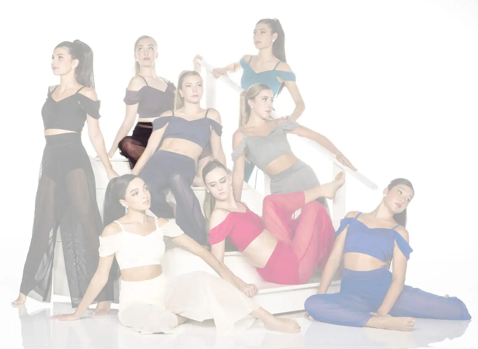 Eight women in colorful dance outfits posing on white stairs