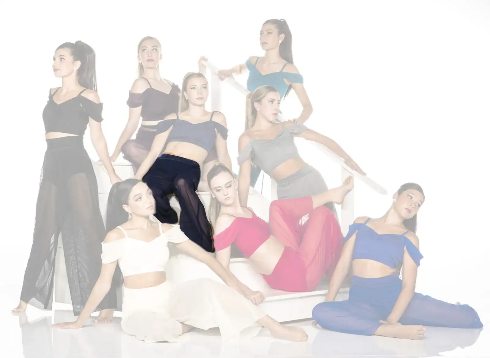 Nine women pose in colorful dance outfits on white stairs.