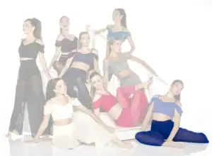 Eight dancers posing on white stairs in colorful outfits