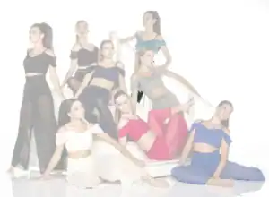Eight dancers pose in colorful costumes on white stairs.