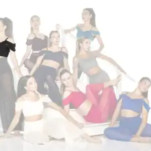 Eight dancers in colorful outfits pose on a white staircase.