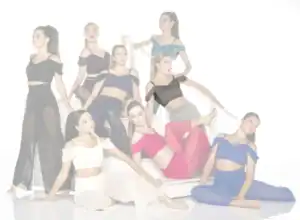 Eight women pose in colorful dance outfits on white stairs.