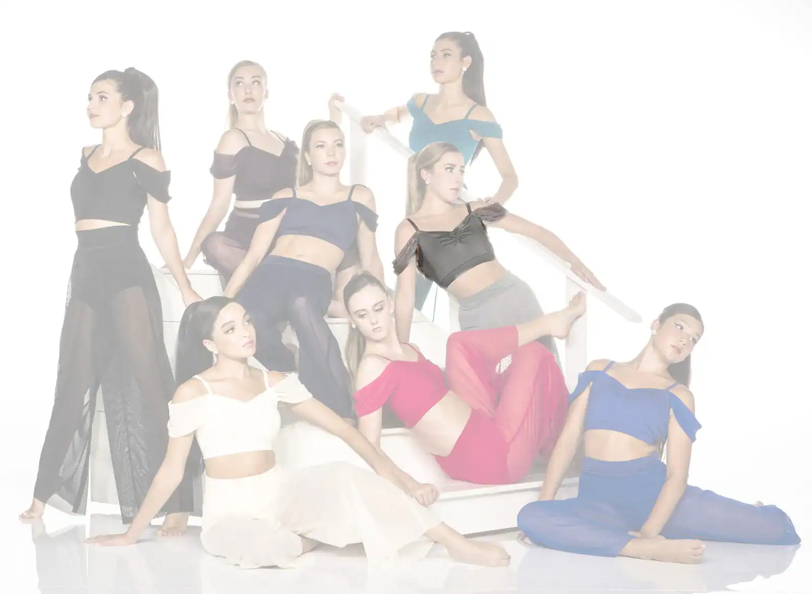 Eight women pose in colorful dance outfits on white stairs.