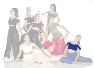Eight women posing on white stairs in colorful dancewear
