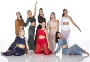 Eight female dancers pose in colorful contemporary dance costumes.