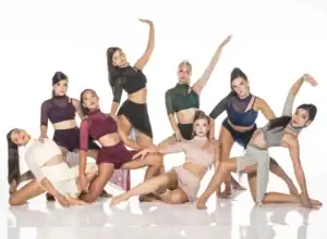 Seven female dancers posing in colorful contemporary costumes