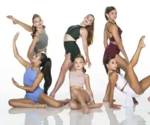 Six young dancers pose in colorful costumes against white background.