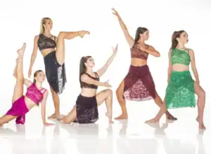 Five dancers posing in colorful lace costumes