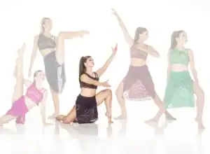 Five dancers posing in colorful lace costumes