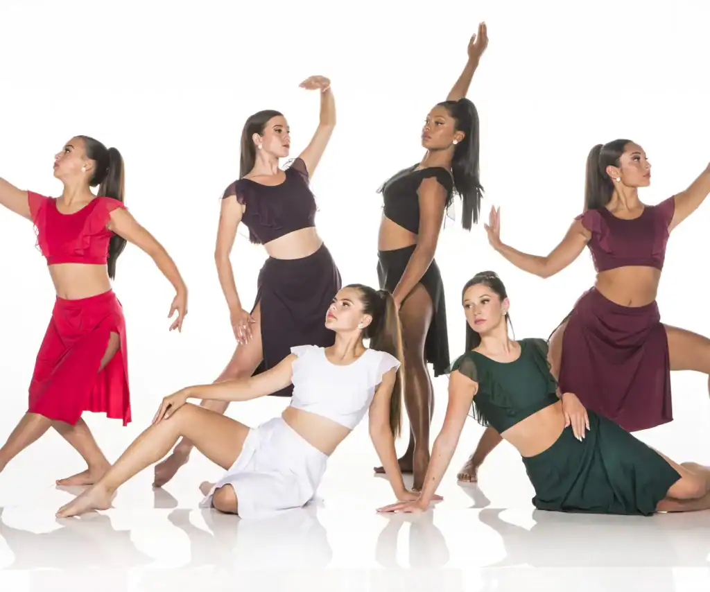 Six dancers pose in colorful costumes against white background.