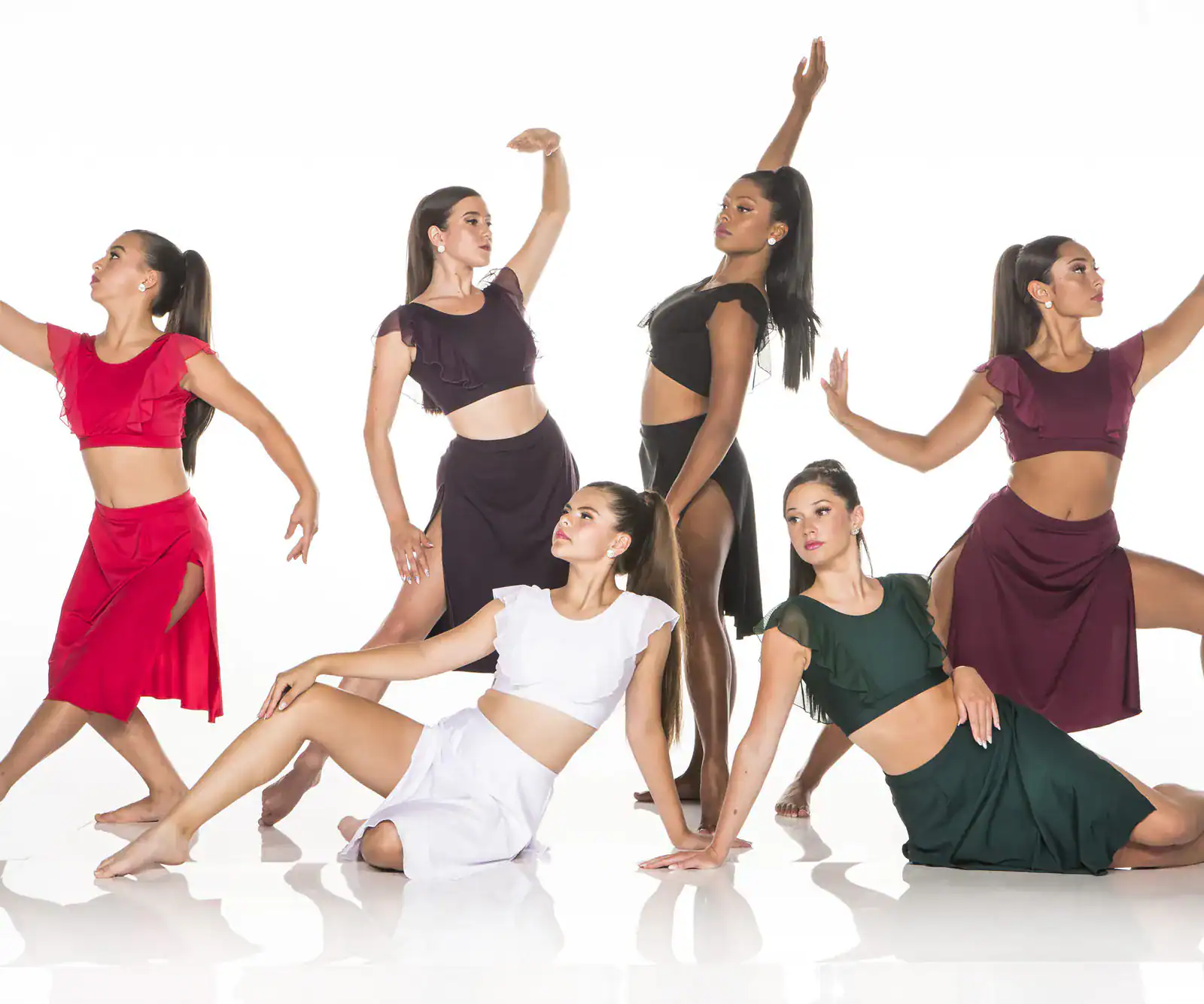Six dancers pose in colorful costumes against white background.