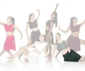 Six dancers posing in colorful costumes against a white background