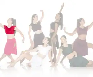 Six female dancers posing in colorful costumes against white background