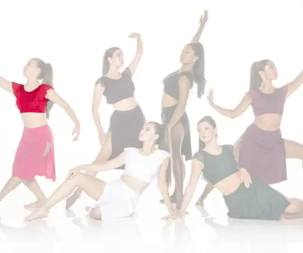 Six female dancers posing in colorful costumes against white background