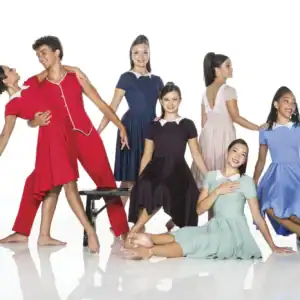 Dancers in colorful vintage costumes pose in a studio