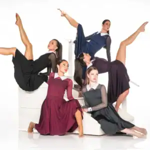 Five dancers pose on white stairs in flowing dresses