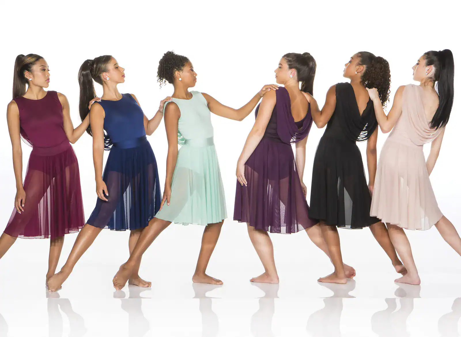 Six women model colorful chiffon dresses in a studio.