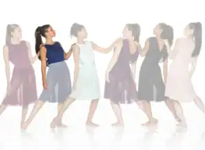 Six women in colorful dresses pose in a line