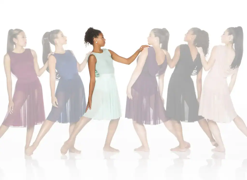 Six women wearing flowing dresses stand in a line.
