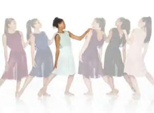 Six women wearing flowing dresses stand in a line.