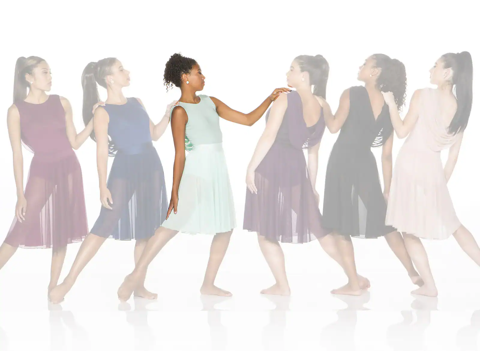 Six women wearing flowing dresses stand in a line.