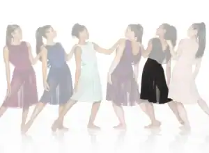 Six women wearing flowing dresses pose in a line