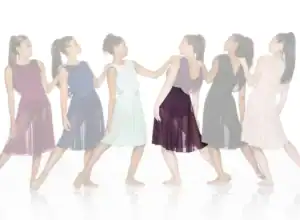 Six women in colorful flowing dresses walking in a line