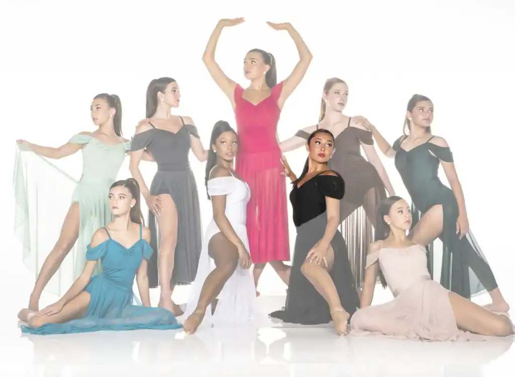 Nine dancers pose in colorful flowing dresses against white backdrop.