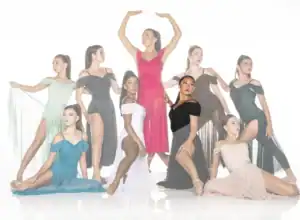 Nine dancers pose in colorful flowing dresses against white backdrop.