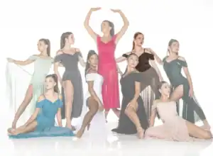 Nine dancers pose in colorful flowing dresses against white background.