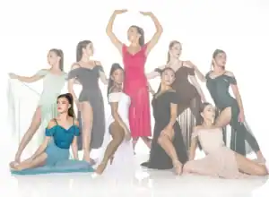 Nine dancers pose in colorful flowing dresses against white backdrop.