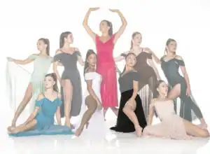 Nine dancers posing in colorful flowing dresses against white background