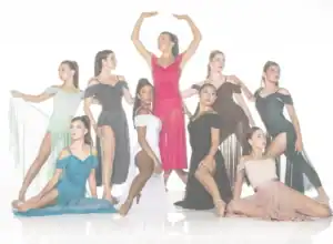 Nine dancers pose in colorful flowing dresses against white background.