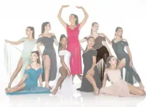 Nine dancers pose in colorful dresses against white background.
