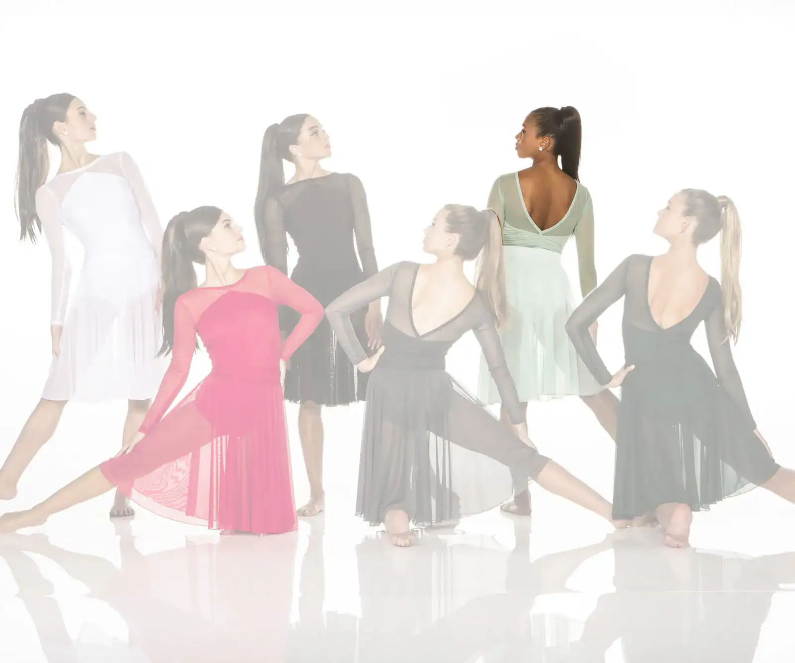 Six women modeling flowing dance dresses in a studio