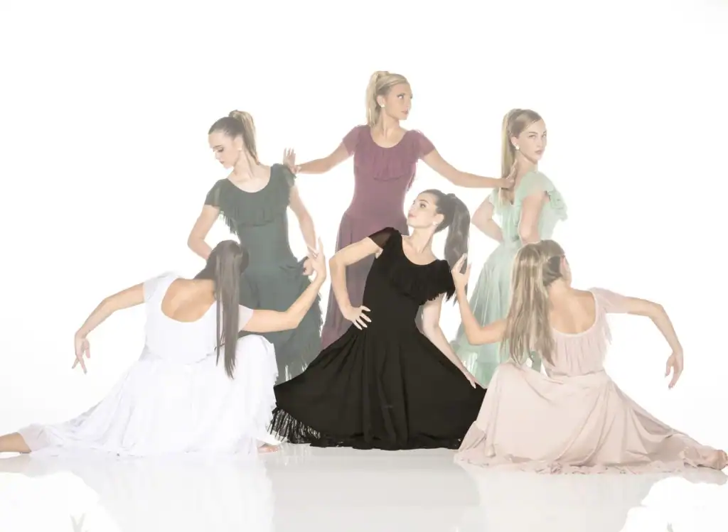Six women pose in flowing dresses against white background.