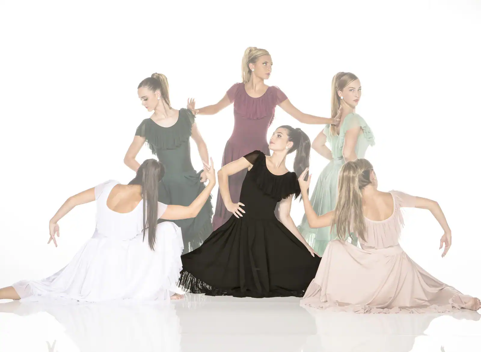 Six women pose in flowing dresses against white background.