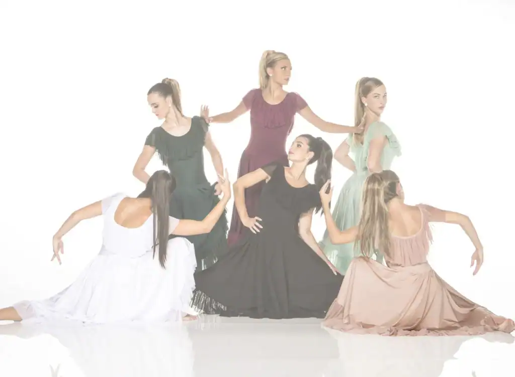 Six women pose in flowing ruffled dresses against white background.
