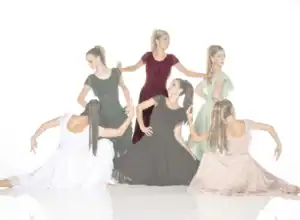 Six women in flowing dresses pose against a white background.