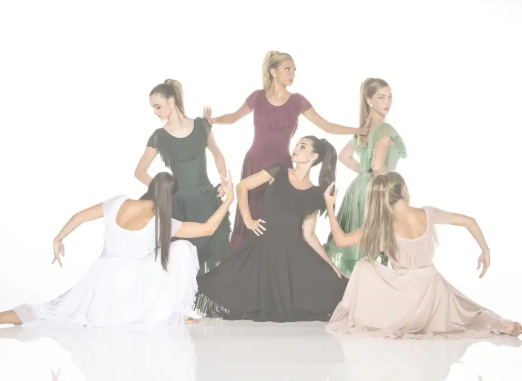 Six women in colorful flowing dresses pose like dancers.