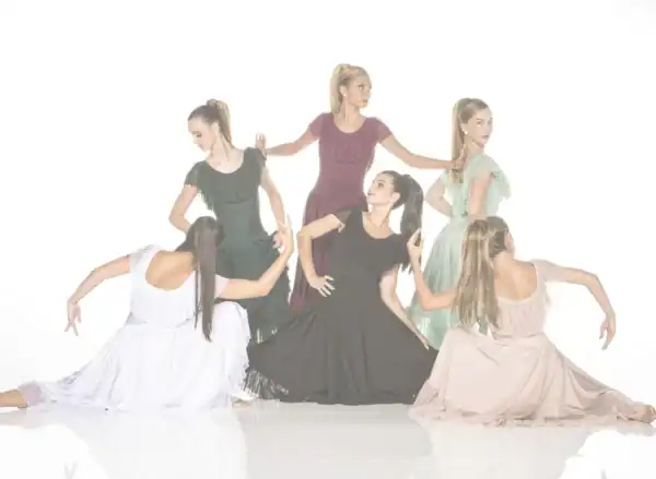 Six women pose in flowing dresses against white background.