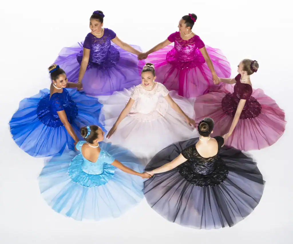 Seven dancers in colorful dresses hold hands in a circle.